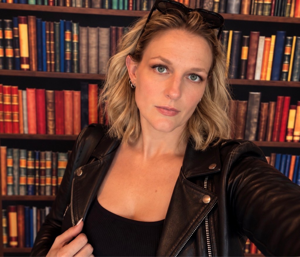A photo of bibliosizzle in front of a bookcase.